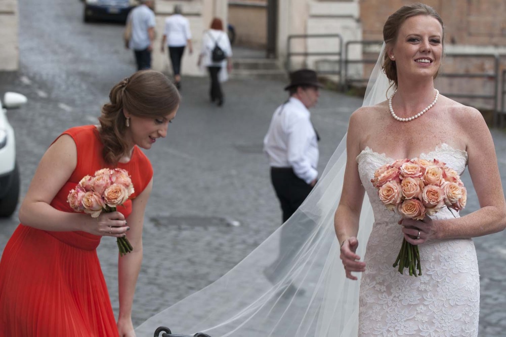 a lovely picture of the bride and her bridesmaid while adjusting the bride veil before the ceremony