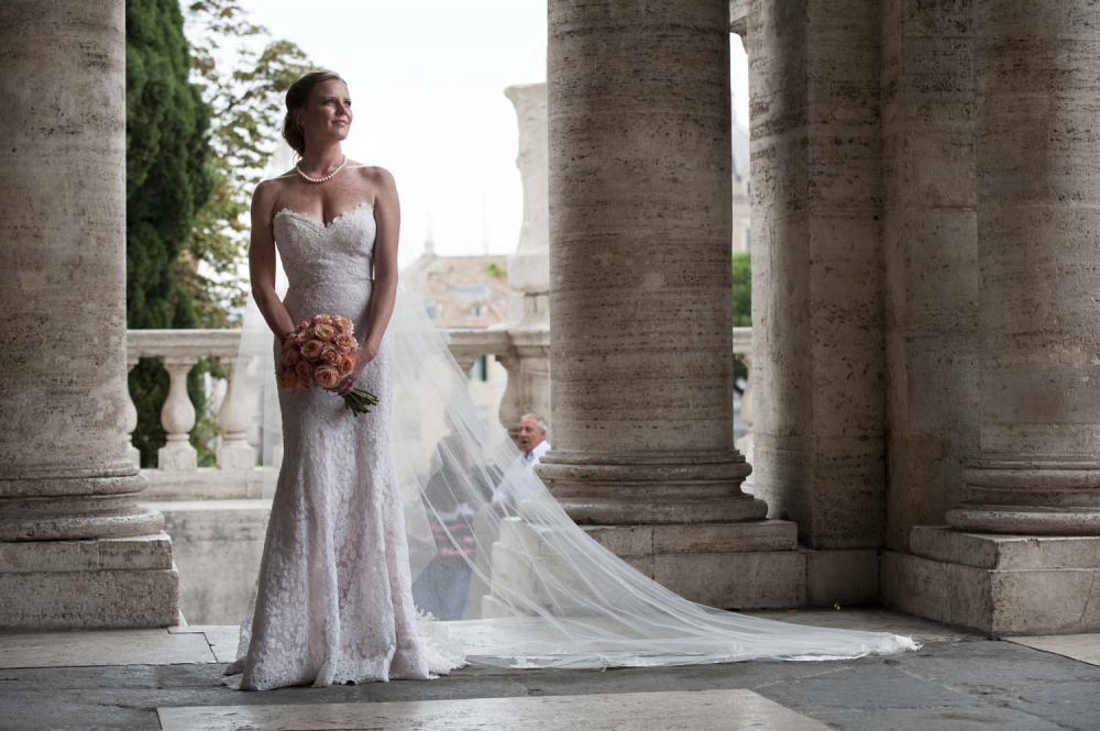 Bride with long dress and a peach color bouquet in a portrait in Rome