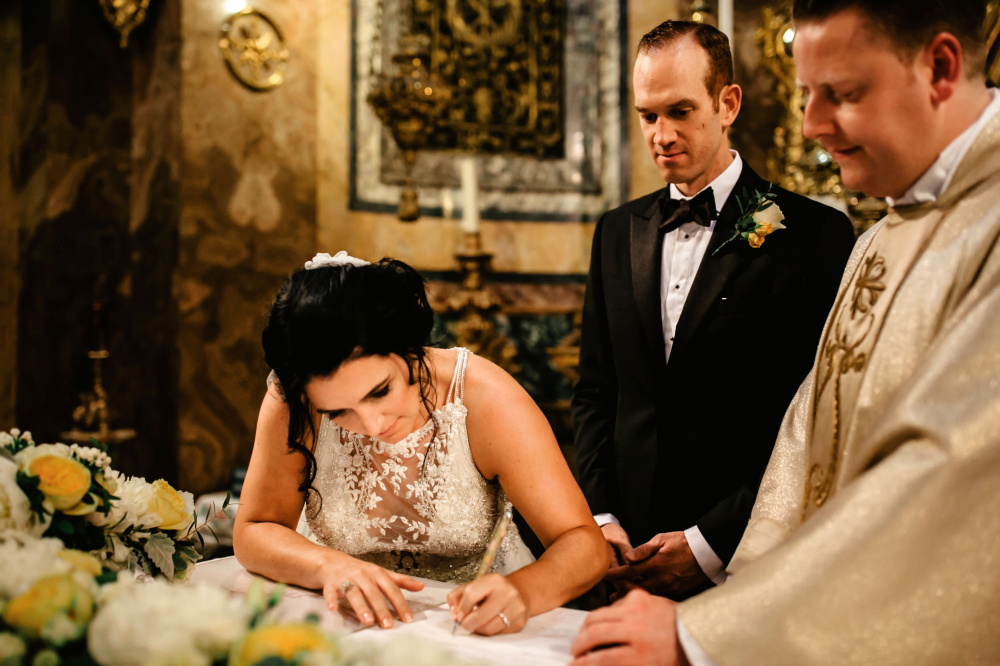 Bride while signin the wedding papers on altar table finely decored with flowers