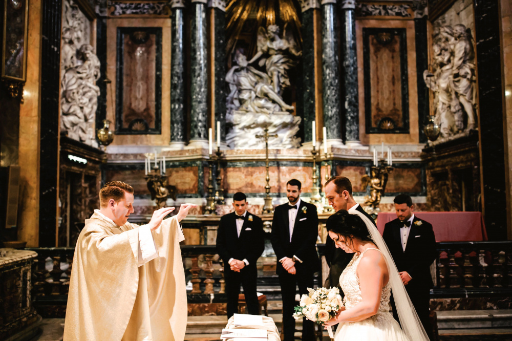 Blessing moment during wedding ceremony with bernini's sculpural masterpiece on the back