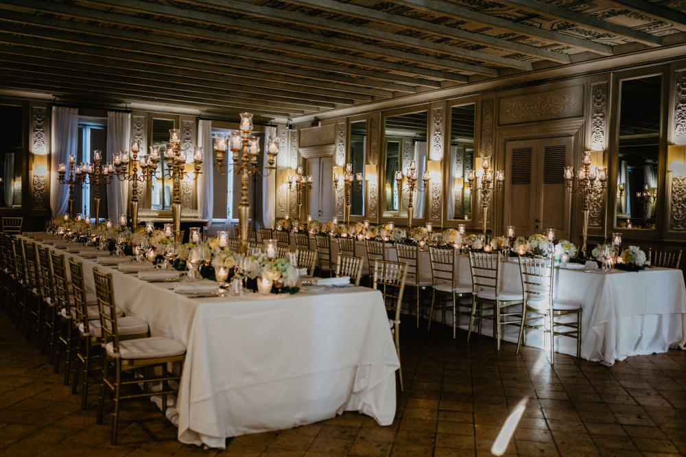 wedding dinner set-up with rectangular tables with gold candelabras in a ballroom in Rome