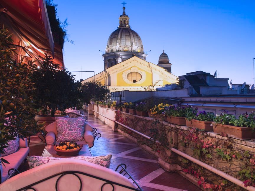 restaurant's greeny Roof terrace by night pinky lightnings, patio sofas, view over churche's facade