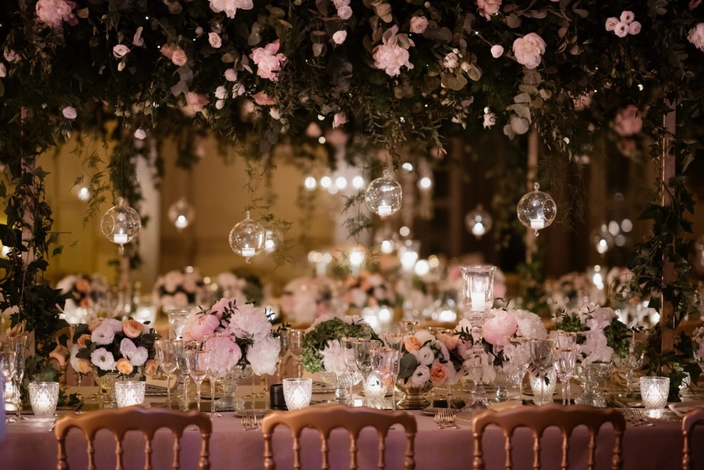 Wedding decor with hanging candles, cascading greenery and pink and ivory flowers