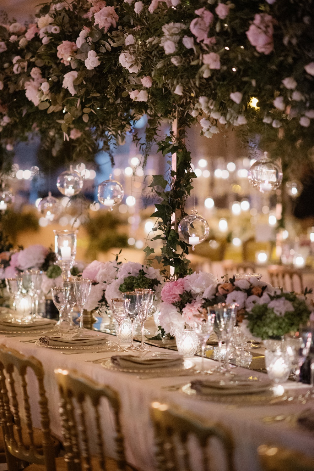 Table setting with ivory and pink flowers, hanging candles and cascading greenery