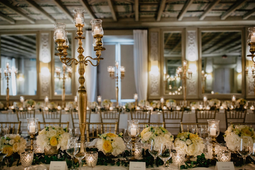 Gold candelabras, white and yellow flowers and gold chair as wedding decor in Rome