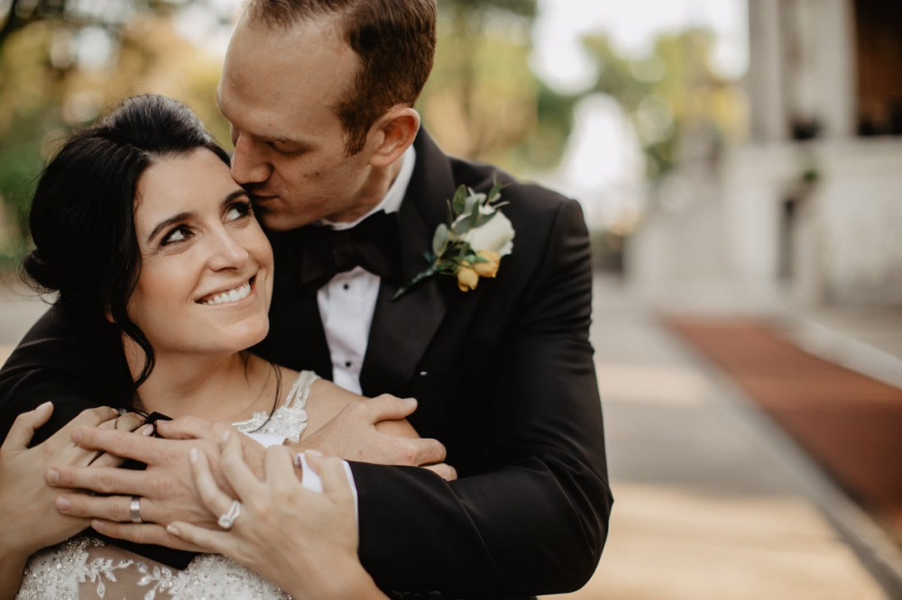 The groom hugs and kisses the bride