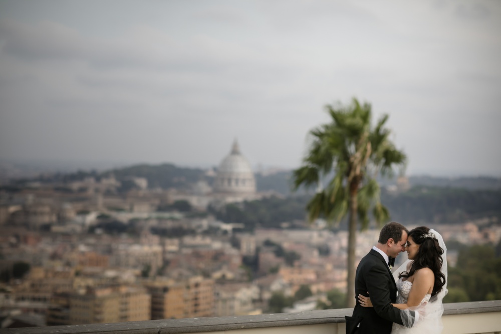 Bride and groom with Rome view from the terrace and garden with palms on their wedding day