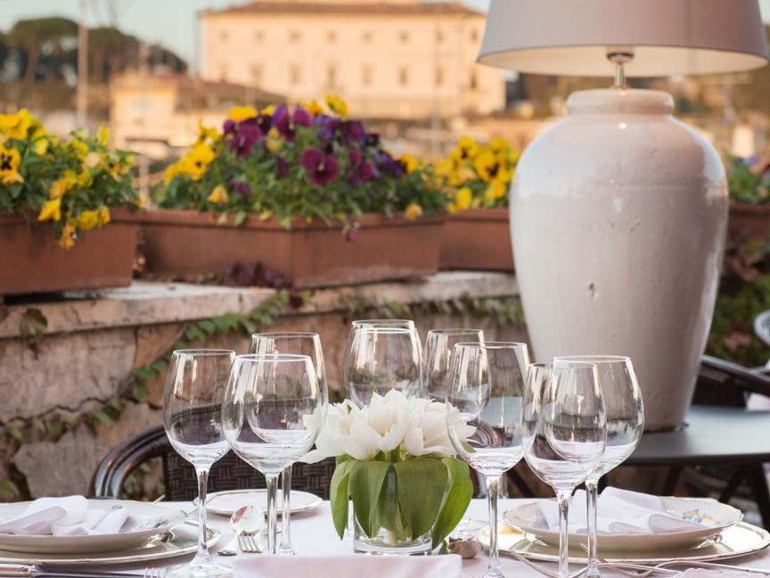 Romantic dinner table set for intimate dinner on a rooftop garden with rome on the background